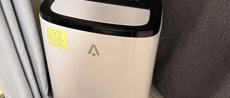 A portable air purifier with a control panel and a small device with a green light.