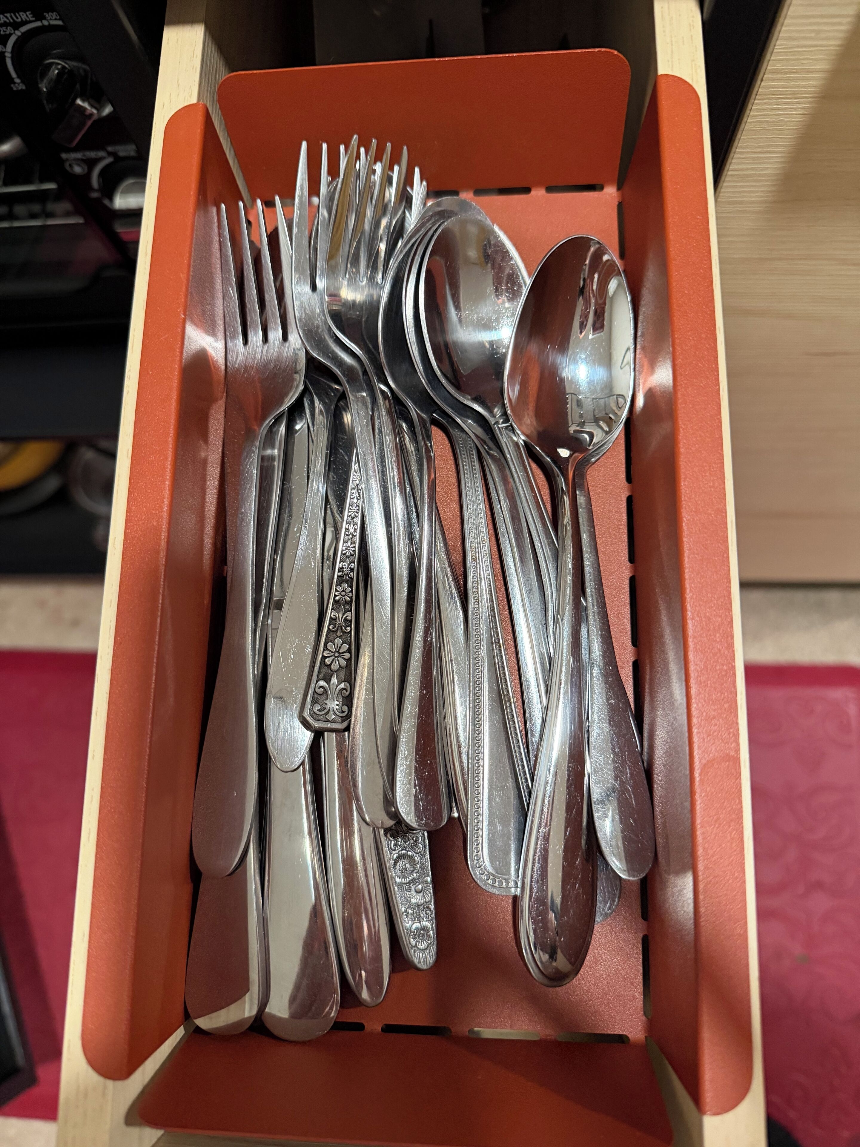 A drawer containing a collection of silverware, including forks, knives, and spoons.