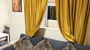 A living room with a sofa, two fur throw pillows, and yellow curtains. - Book one week or more and get 10% discount
Stylish 2 BR Suite in West Seattle!
 (Seattle)