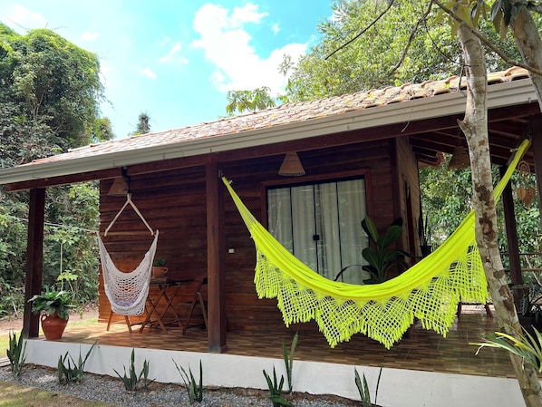 A wooden cabin with a porch, a hammock, and a potted plant. - Pousada e Restaurante Sumaúma (Santarém)