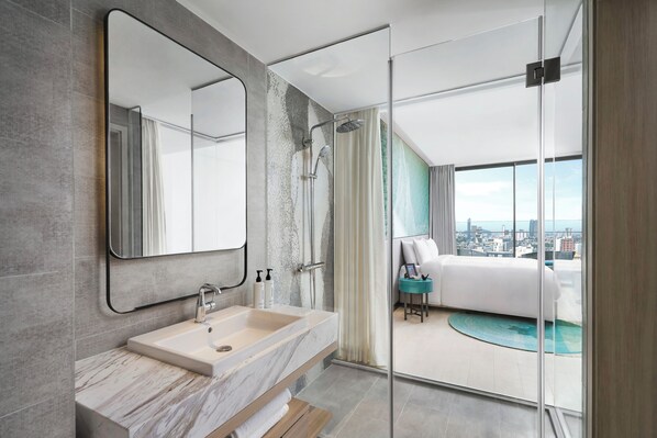 Un baño moderno con un espejo grande, un lavamanos y una ducha.