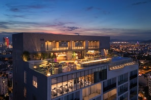 A multi-story hotel with a rooftop lounge area, a pool, and a city view. - voco Ma Belle Danang by IHG (Da Nang)