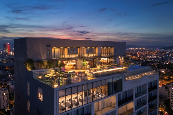 A multi-story hotel with a rooftop lounge area, a pool, and a city view. - voco Ma Belle Danang by IHG (Da Nang)