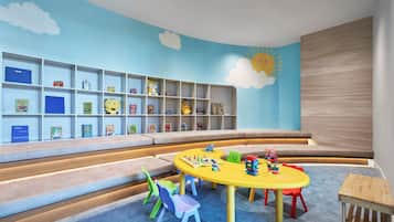 A children's play area with a bookshelf, colorful chairs, and a yellow table.