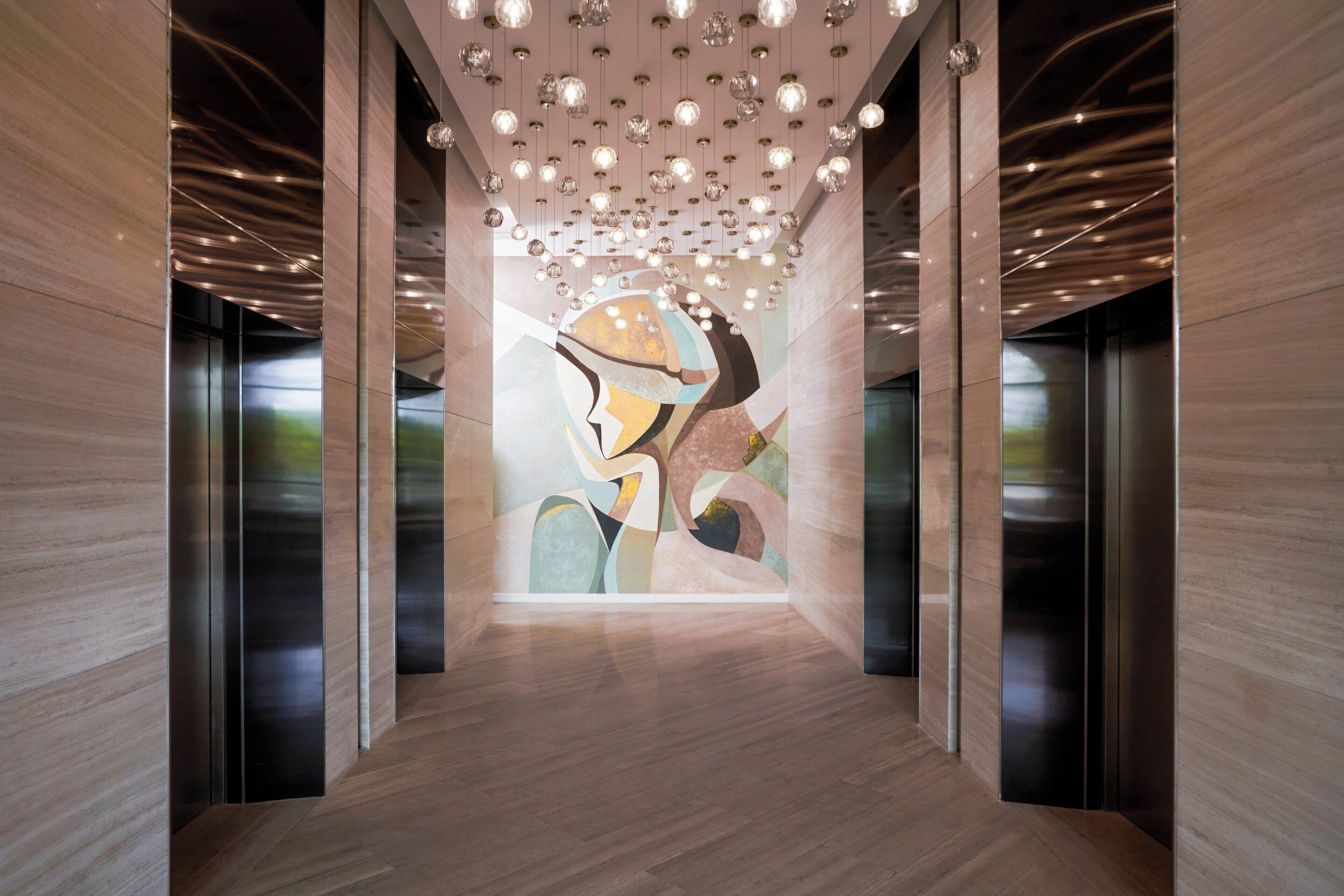 A hallway with a modern design, featuring a central abstract art piece on the wall and a ceiling with hanging spherical lights.