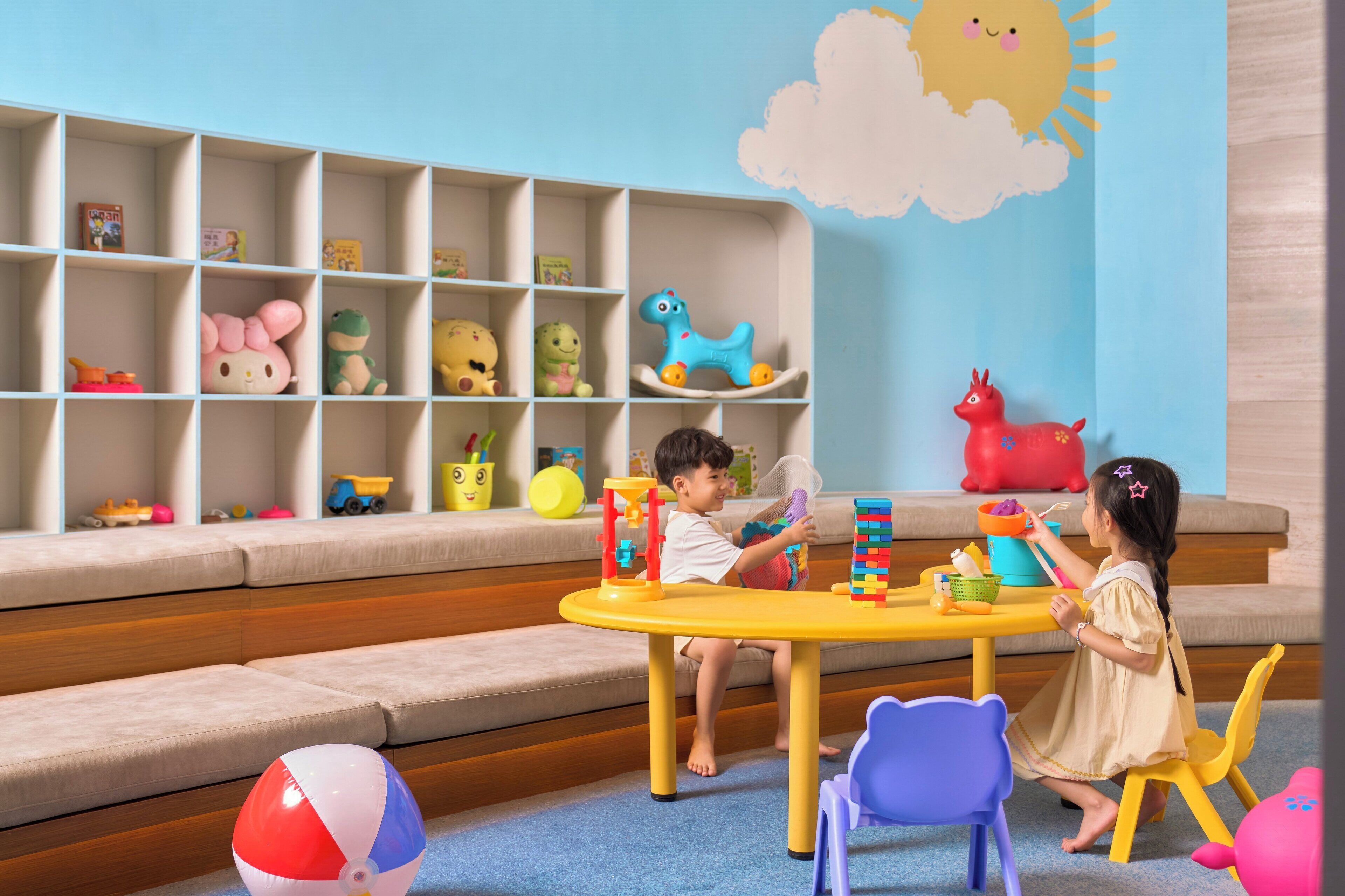 A children's play area with a bookshelf, a play table, and a sofa.