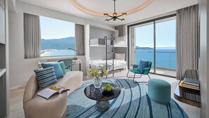 A modern hotel room with a balcony, a sofa, a coffee table, and a view of the sea. - voco Ma Belle Danang by IHG (Da Nang)