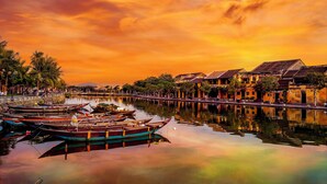 A calm river with boats, traditional buildings, and a clear sky. - voco Ma Belle Danang by IHG (Da Nang)