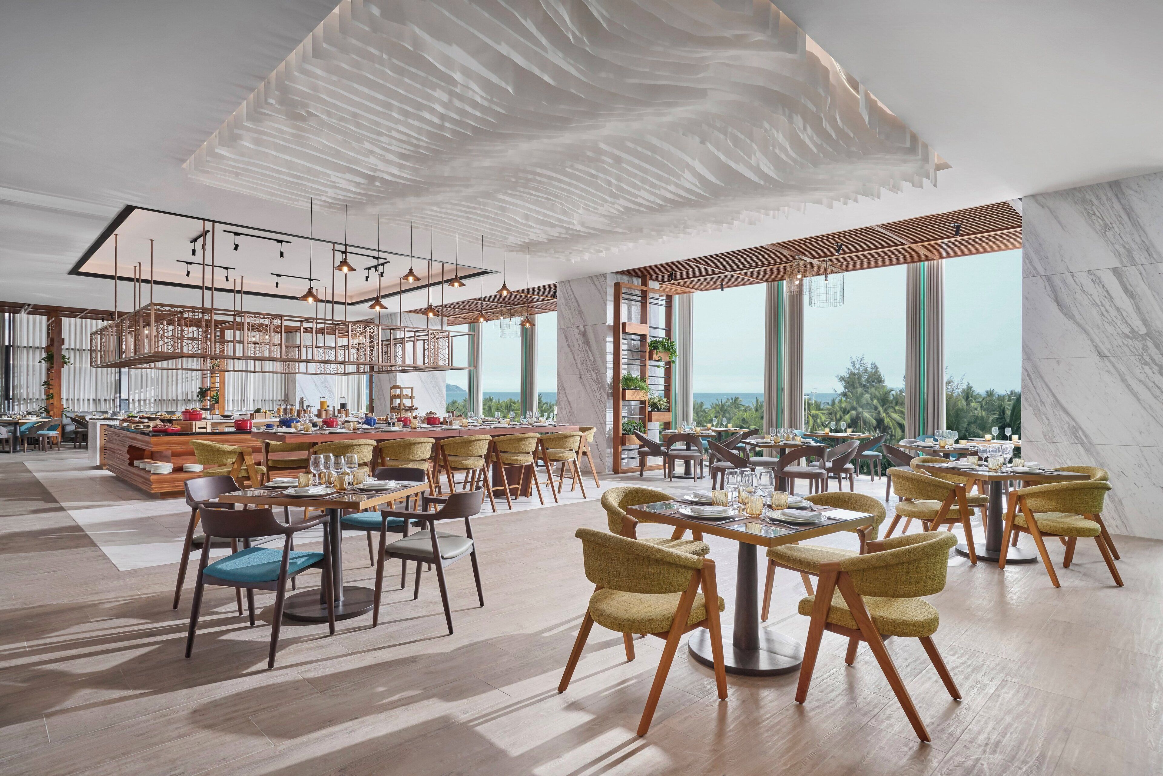 A spacious dining area with high ceilings, modern lighting, and large windows offering views of the outdoors.