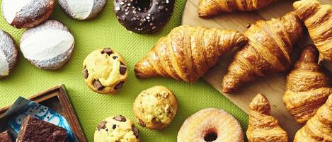 A variety of baked goods including cookies, chocolate-covered doughnuts, and croissants.
