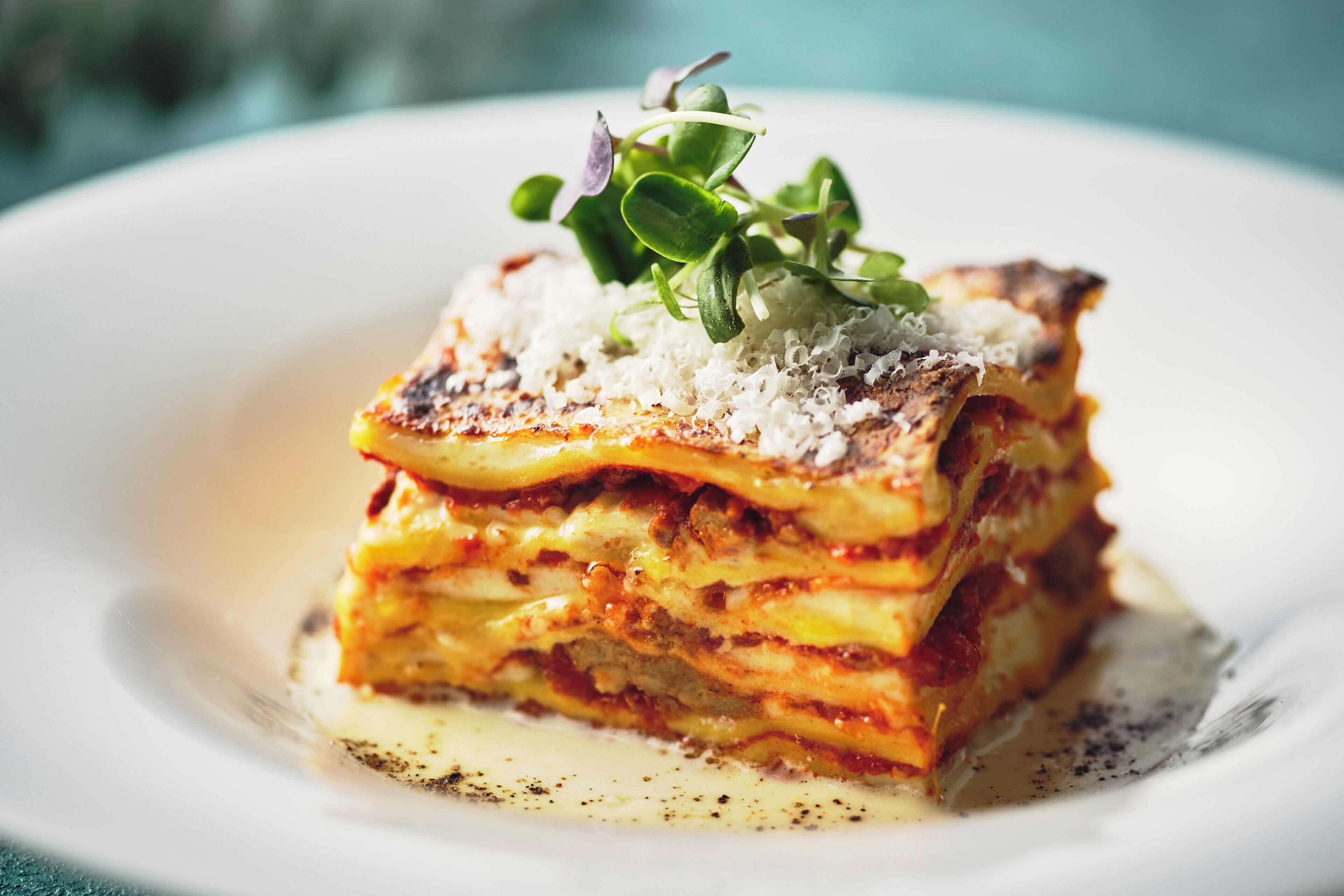 Eine Lasagneplatte mit grünem Belag und Käse.