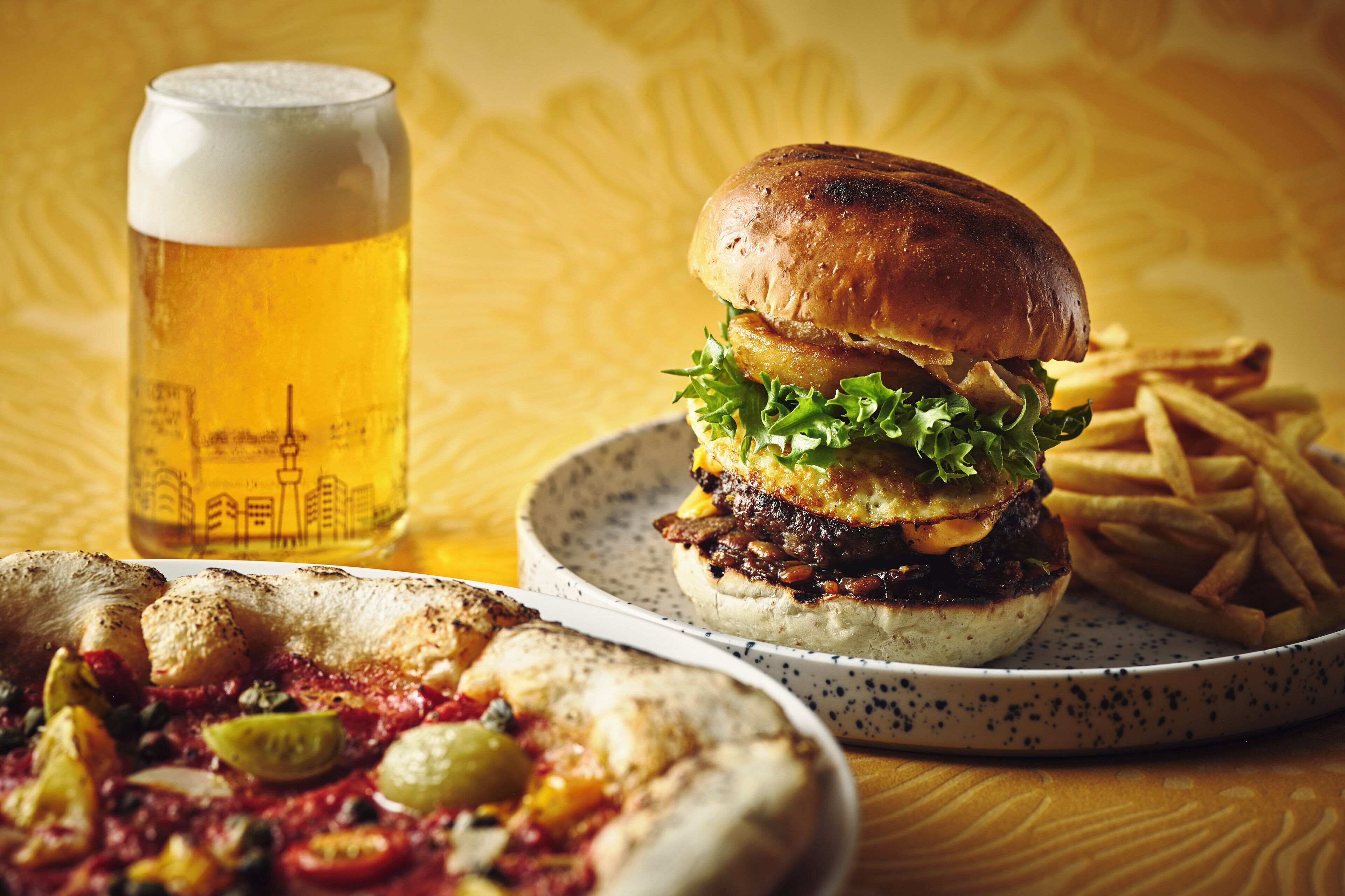 A burger, fries, and a beer glass on a table.