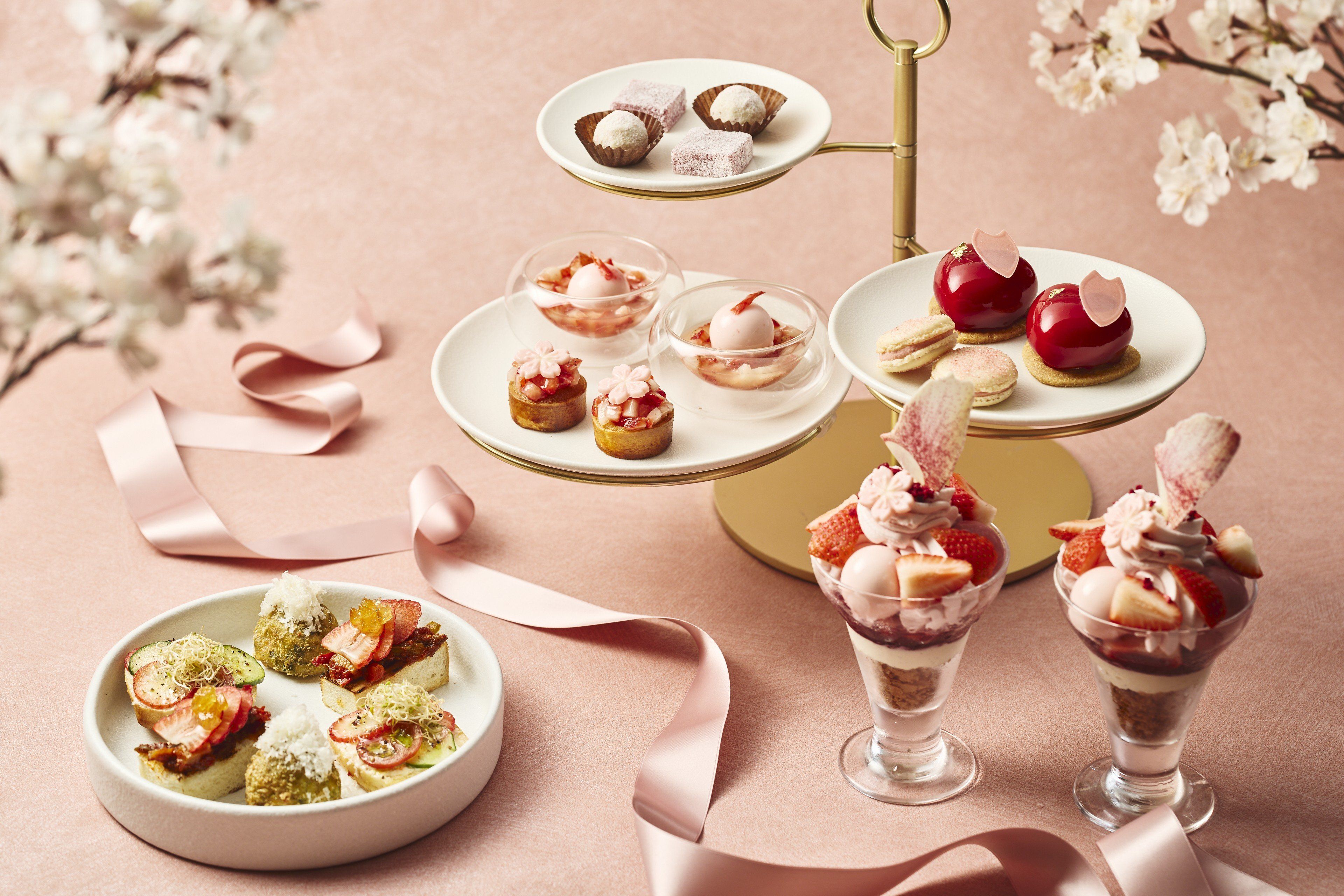 A variety of desserts on a table with a pink background.