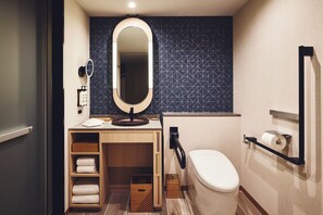 Un baño pequeño con inodoro, lavamanos con espejo, toallero y estante con toallas dobladas.