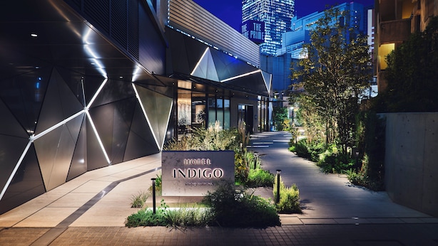 The exterior of Hotel Indigo Tokyo Shibuya, featuring a modern architectural design with geometric patterns and a well-lit entrance.