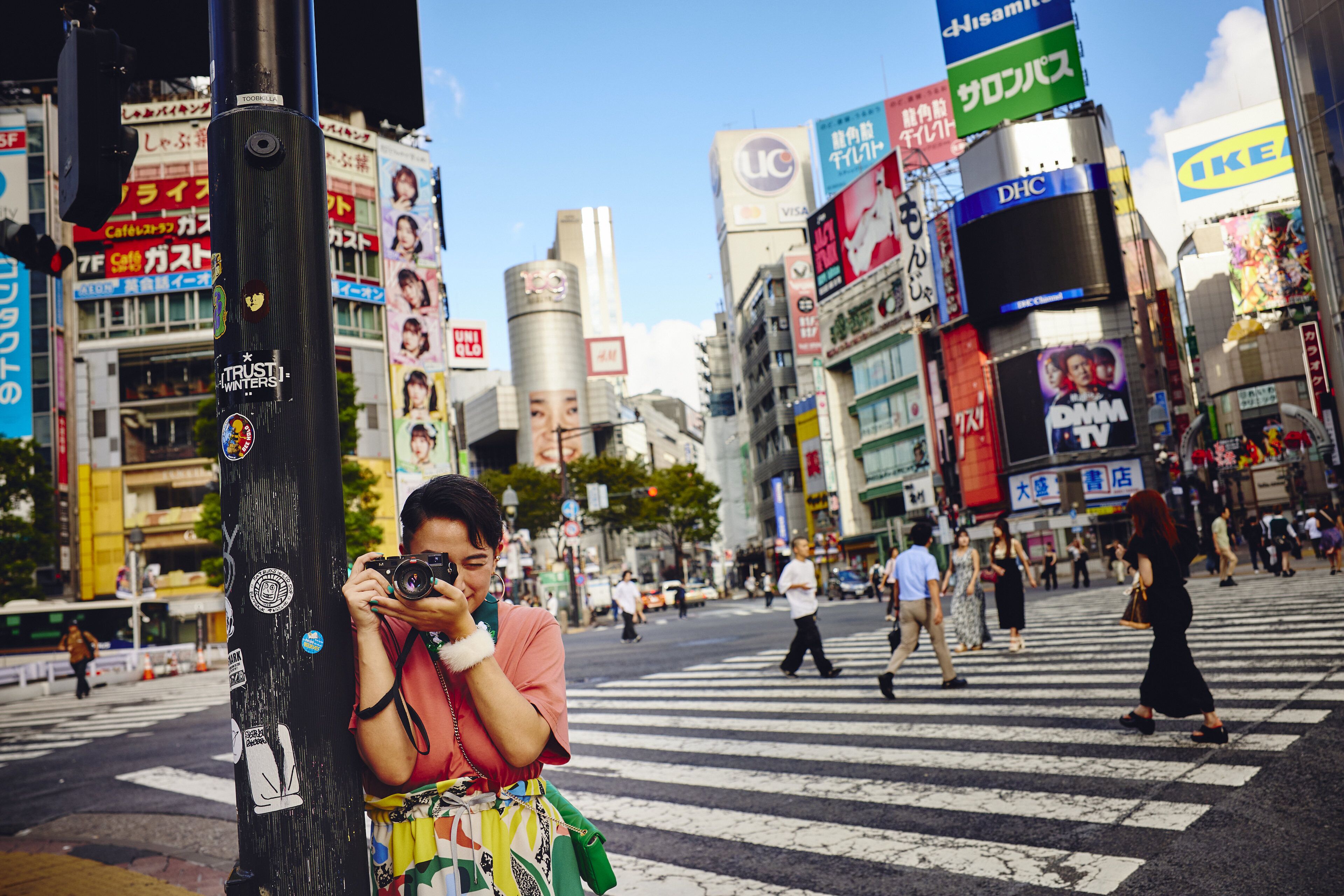 A busy urban street scene with pedestrians crossing a zebra crossing.