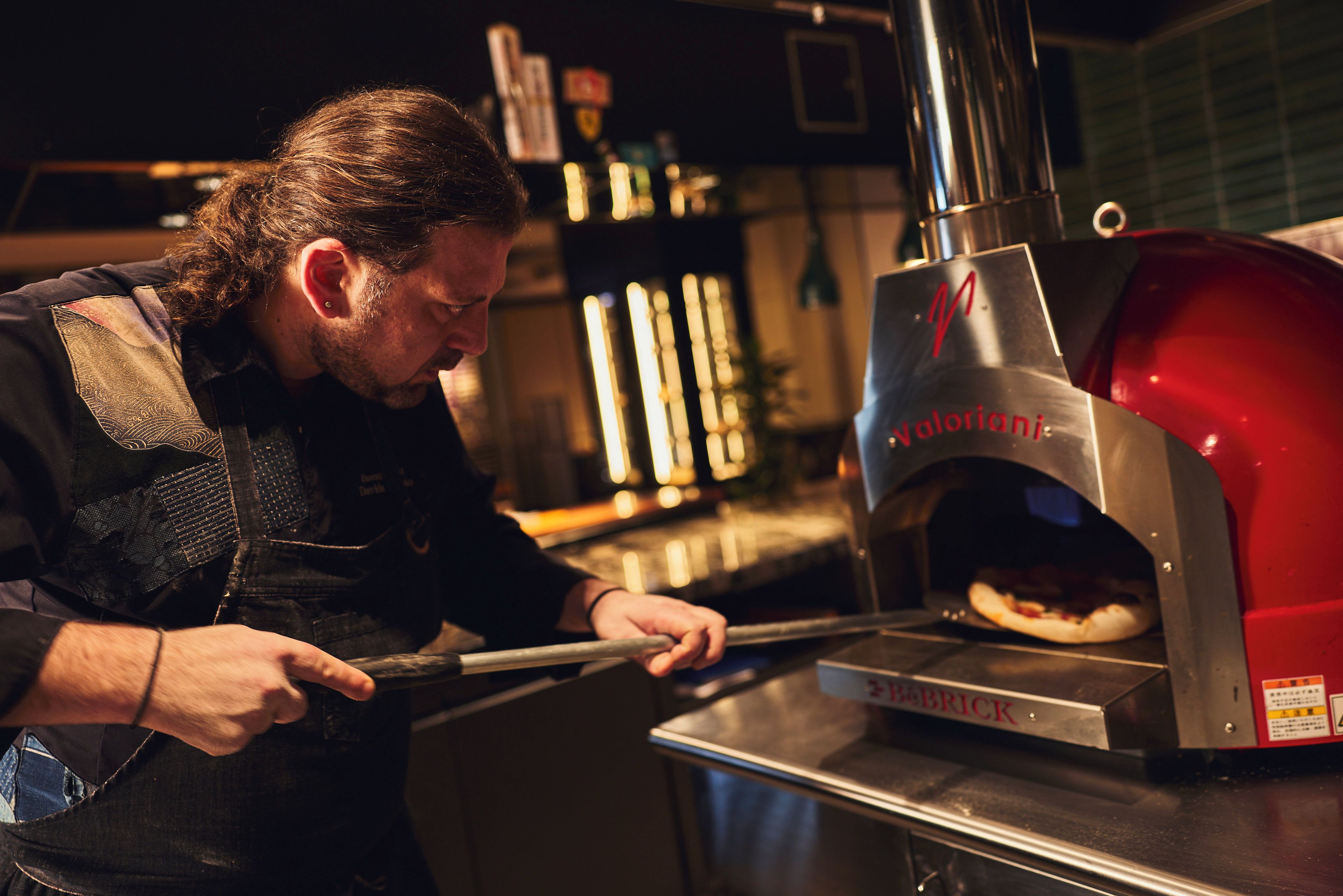A person operating a brick oven pizza oven.