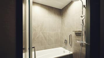 A modern bathroom with a bathtub, shower, and glass door.