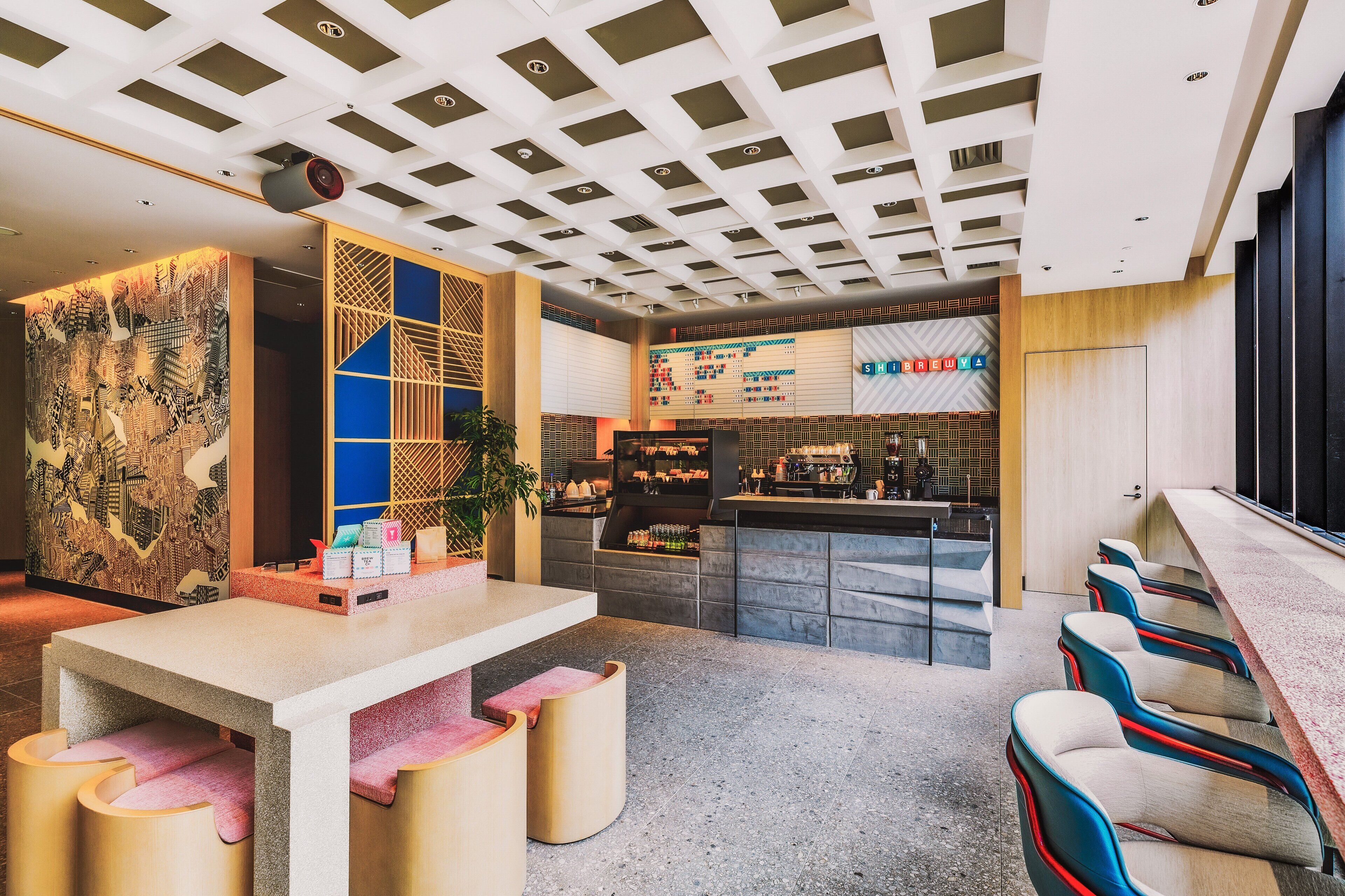 Un espace bar moderne doté d’un long comptoir, de tabourets de bar et d’un mur décoratif orné de motifs géométriques.