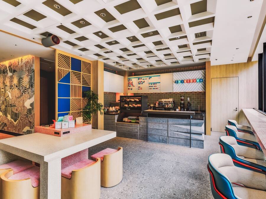 Un espace bar moderne doté d’un long comptoir, de tabourets de bar et d’un mur décoratif orné de motifs géométriques.