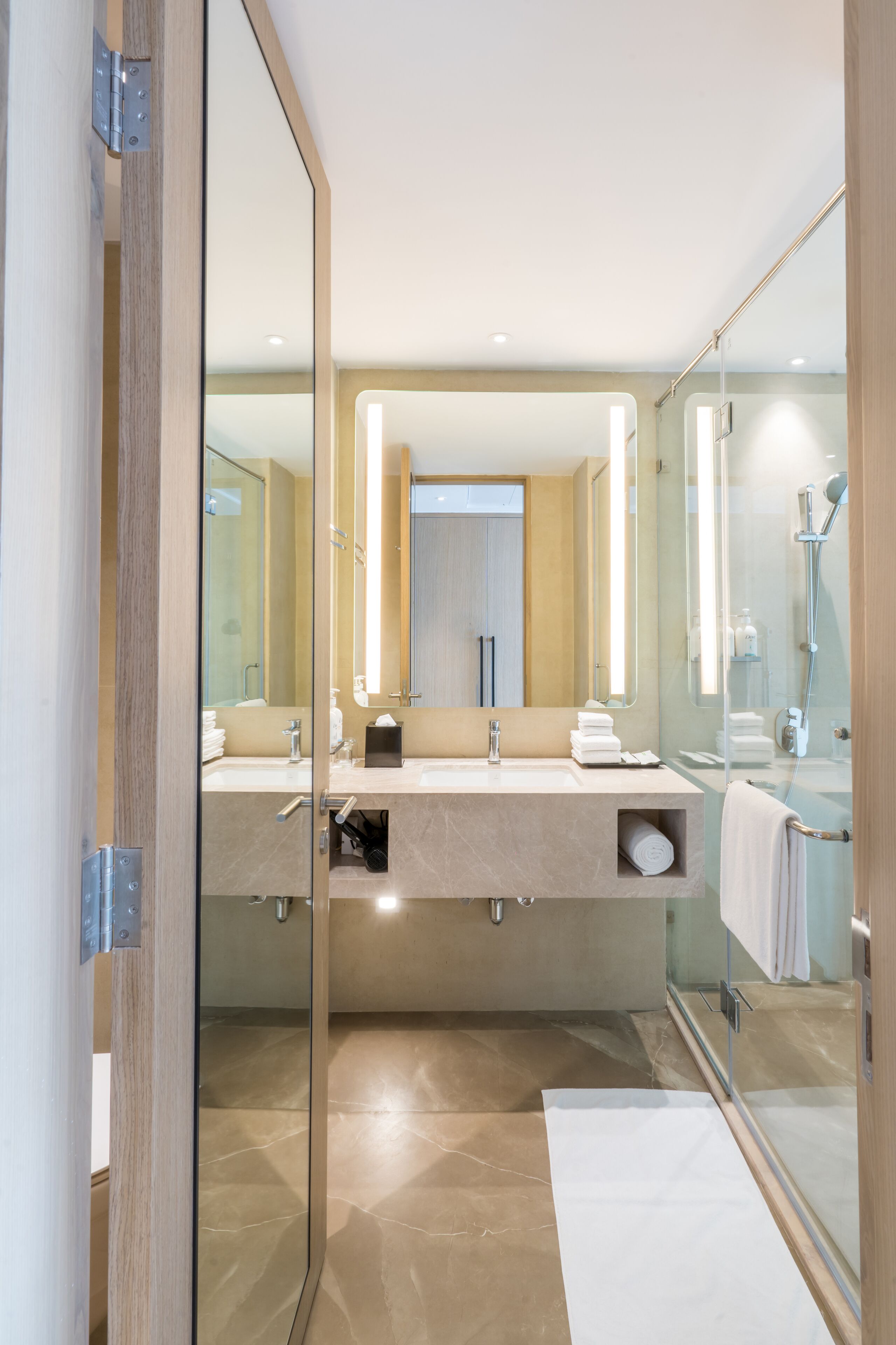 A modern bathroom with a glass shower enclosure, dual sinks, and a large mirror.