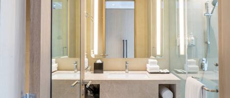 A modern bathroom with a glass shower enclosure, dual sinks, and a large mirror.
