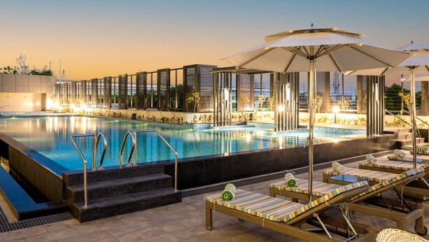 A poolside area with lounge chairs, umbrellas, and a pool.