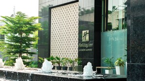 A Holiday Inn at Lucknow Airport with a modern facade, water features, and potted plants.