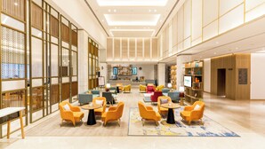 A spacious lobby with multiple seating areas, a reception desk, and a television screen.