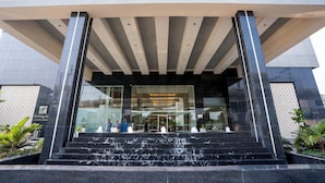A modern building entrance with a glass facade, a water feature at the base of the steps, and a sign indicating it is a Holiday Inn Express.