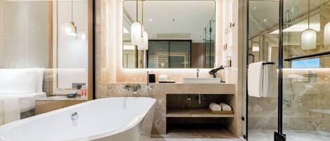 A modern bathroom with a freestanding bathtub, a glass-enclosed shower, and a large mirror above the sink.