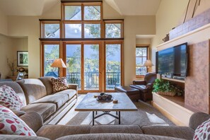 A spacious living room with a large window, a flat-screen TV, and a comfortable seating area. - Aspen Ridge 3 3 Bedroom Townhouse by Alpine Lodging Telluride (Telluride)