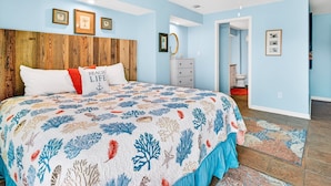 A bedroom with a bed, a ceiling fan, and a door leading to a bathroom.