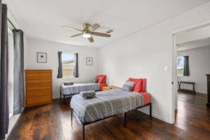 Una habitación con dos camas, un ventilador de techo y un aparador de madera.