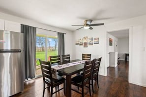 Comedor con mesa, sillas, refrigerador y vistas al exterior.