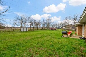 A backyard with a grassy lawn, a barbecue grill, and a shed. - FW Monthly + WiFi + Desk + Pet Backyard (Fort Worth)