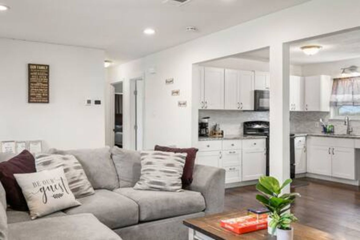 A modern living room with a sofa, a coffee table, and a kitchen area with white cabinets.