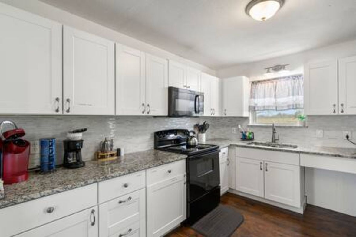 A kitchen with white cabinets, a black stove, and a microwave.