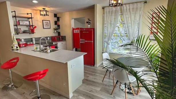 A modern kitchen with a central island, red refrigerator, and bar stools. - LemonTree Cottage firepit and hottub, 8 minutes from the beach (New Smyrna Beach)