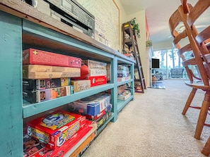A room with a bookshelf filled with board games and puzzles. There is a wooden chair and a ladder leaning against the wall. - Riverfront Retreat with Gorgeous View (Rocky Point)