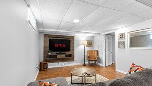 Una sala de estar moderna con un televisor de pantalla plana, una mesa de centro de madera y un sofá cómodo.