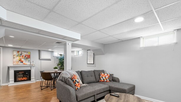 Una sala moderna con un sofá seccional gris, una mesa de centro redonda y una chimenea.
