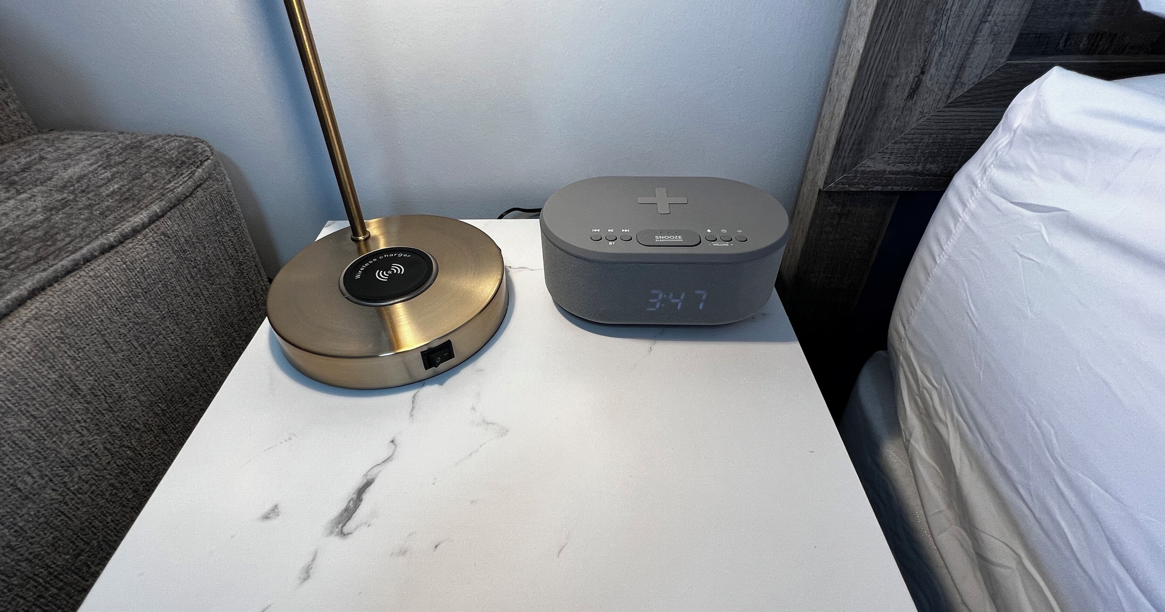 Una mesita de noche con un cargador inalámbrico y un reloj digital que muestra 34:17.