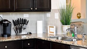 A kitchen with dark cabinets, a granite countertop, a sink, and a potted plant. - Elegant and cozy 3 bedroom/2 full bath new home (San Antonio)