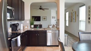 A modern kitchen with dark cabinets, a stainless steel refrigerator, a microwave, and a dishwasher. - Elegant and cozy 3 bedroom/2 full bath new home (San Antonio)