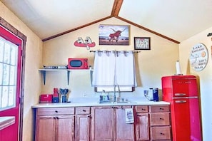 A kitchen with wooden cabinets, a red refrigerator, a microwave, and a window with a red door. - 4  Lakefront, Comfortable Bed, Great Fishing (Eastland)