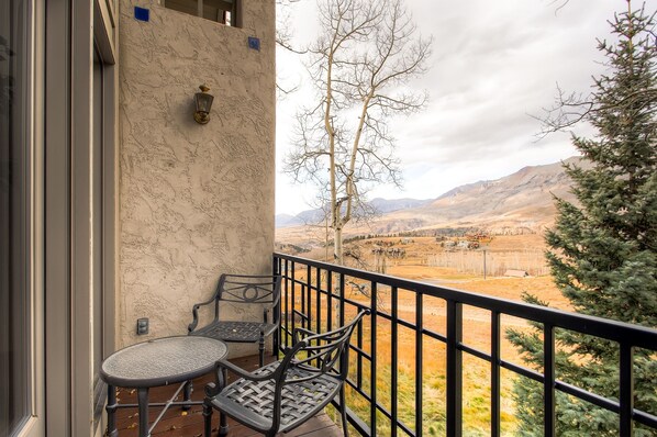 Un balcón con dos sillas y una mesa, con vista a un paisaje montañoso.
