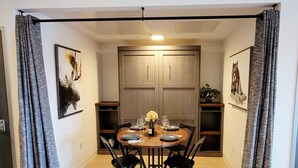 A dining area with a round table, black chairs, and a wooden cabinet. - Bozeman Summer Getaway: Climate-Controlled Garage + Mountain Views! (Bozeman)