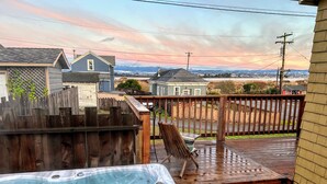 A hot tub on a wooden deck with a view of houses and mountains in the background. - Serenity by the Sea (Samoa)