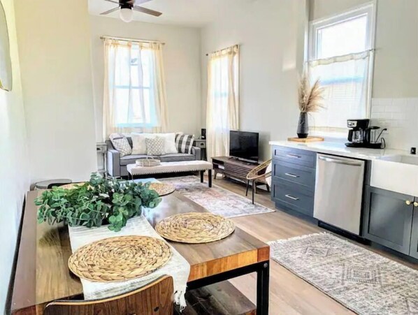 Cozy living space with a dining table, sofa, flat-screen TV, and kitchenette.